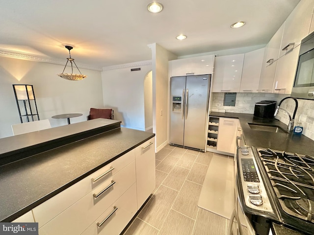 kitchen with sink, stainless steel appliances, pendant lighting, decorative backsplash, and white cabinets