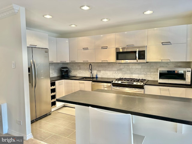 kitchen with white cabinets, backsplash, sink, and appliances with stainless steel finishes