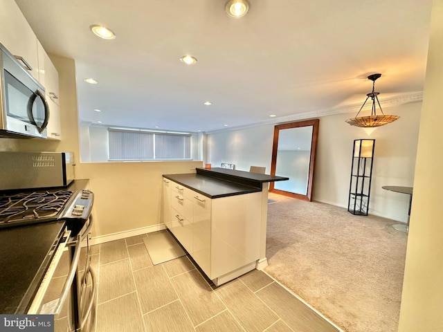 kitchen with kitchen peninsula, decorative light fixtures, light carpet, white cabinets, and appliances with stainless steel finishes