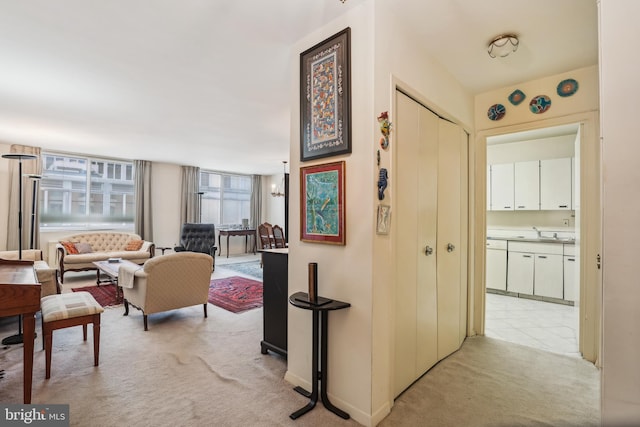 hallway with light colored carpet and sink