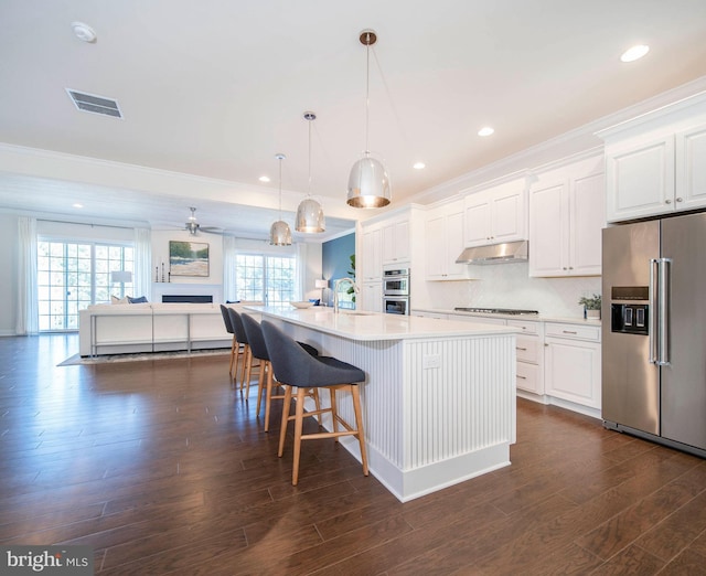 kitchen featuring pendant lighting, dark wood-type flooring, white cabinets, an island with sink, and stainless steel appliances