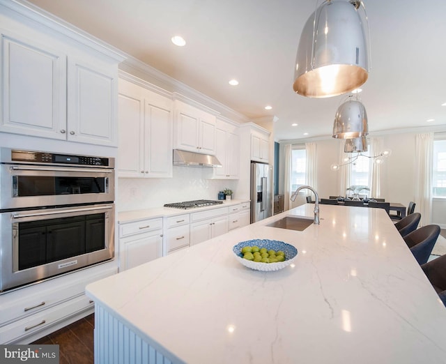 kitchen featuring ornamental molding, stainless steel appliances, sink, white cabinetry, and hanging light fixtures