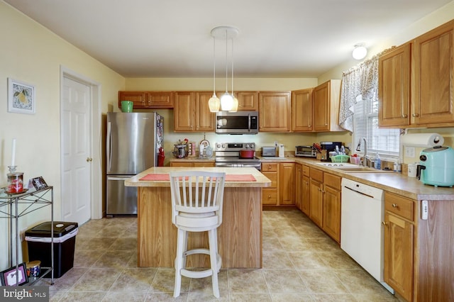 kitchen featuring appliances with stainless steel finishes, a breakfast bar, sink, pendant lighting, and a kitchen island