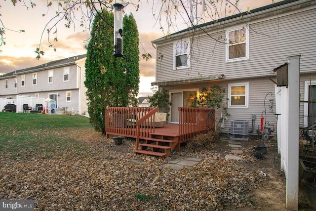 back house at dusk with cooling unit, a yard, and a wooden deck