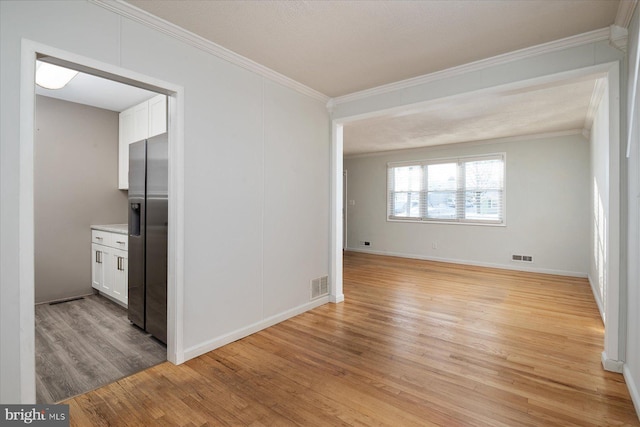 spare room with light hardwood / wood-style flooring and crown molding