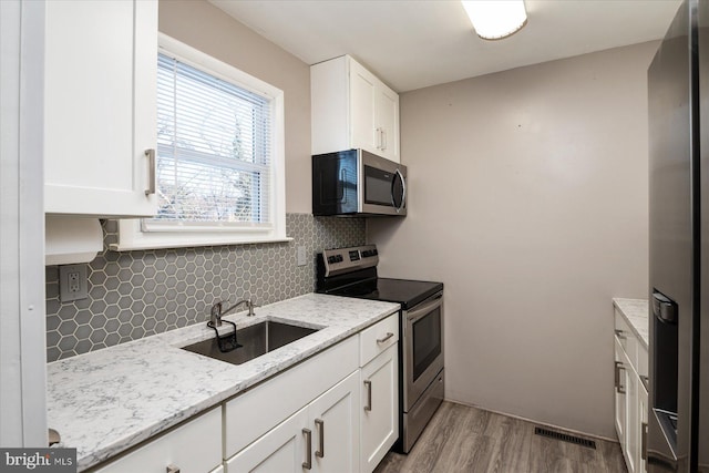 kitchen with white cabinets, decorative backsplash, sink, and stainless steel appliances