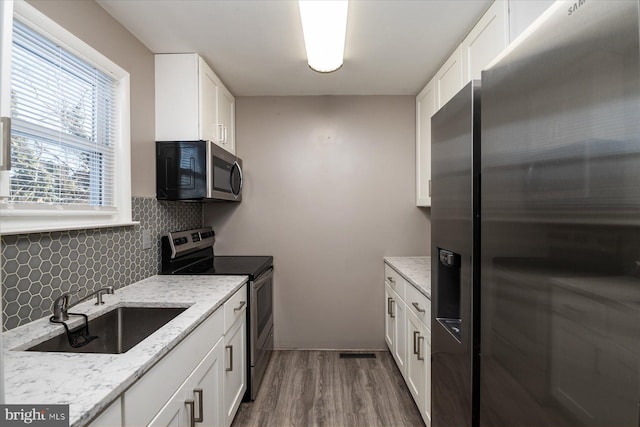 kitchen with white cabinets, appliances with stainless steel finishes, backsplash, and sink