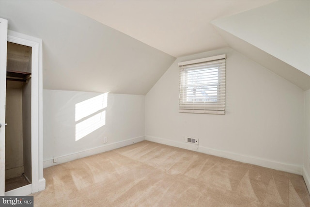 bonus room with light colored carpet and vaulted ceiling