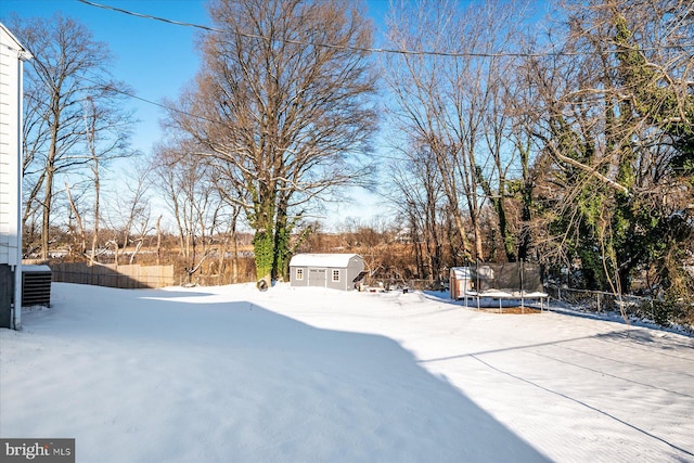 yard layered in snow featuring an outdoor structure and a trampoline