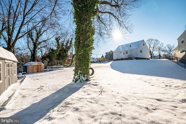 snowy yard with a storage shed and a trampoline