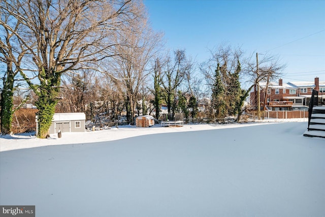 yard covered in snow with a storage unit