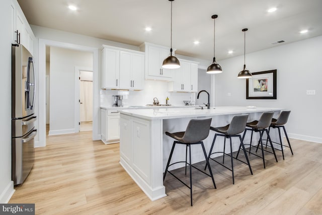 kitchen featuring white cabinetry, an island with sink, and stainless steel refrigerator with ice dispenser