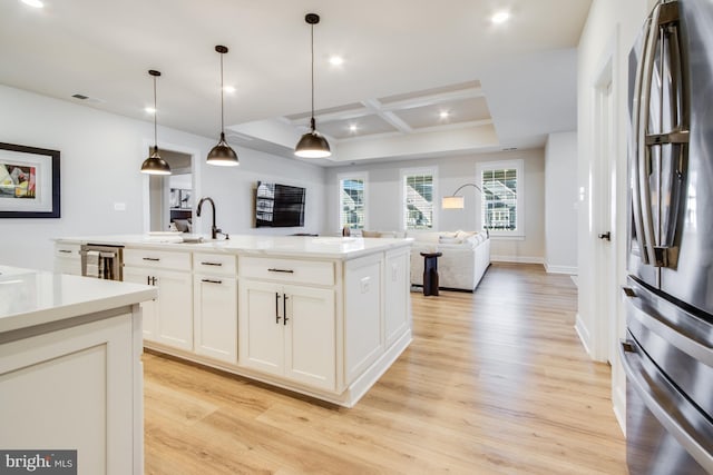 kitchen with stainless steel fridge, coffered ceiling, a kitchen island with sink, decorative light fixtures, and light hardwood / wood-style floors