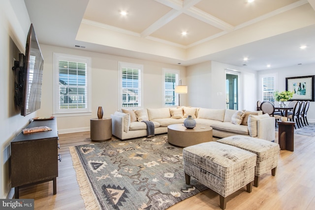 living room with light wood-type flooring, crown molding, a wealth of natural light, and coffered ceiling