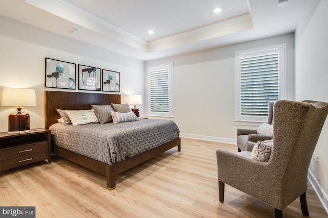 bedroom featuring light hardwood / wood-style floors, a raised ceiling, and ornamental molding