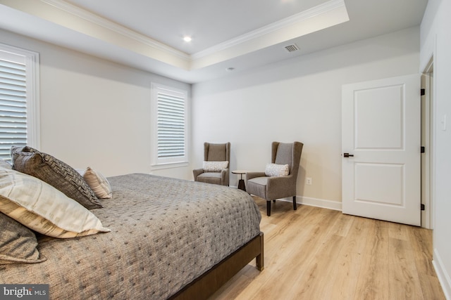 bedroom with a raised ceiling, light wood-type flooring, and ornamental molding