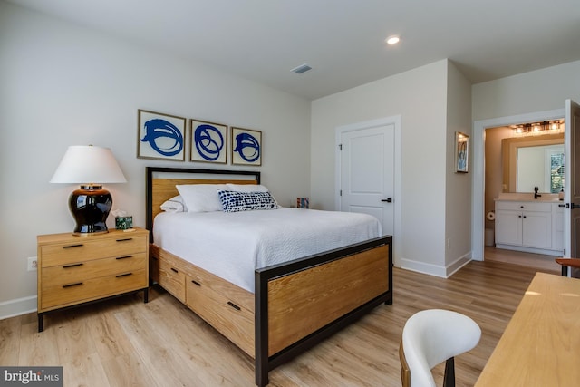 bedroom featuring ensuite bathroom and light hardwood / wood-style flooring