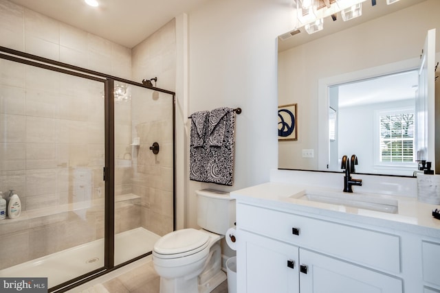 bathroom with vanity, toilet, and a shower with door