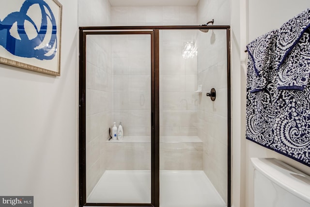 bathroom featuring a shower with door and toilet