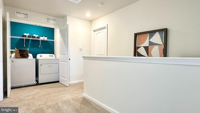 washroom with washing machine and clothes dryer and light colored carpet