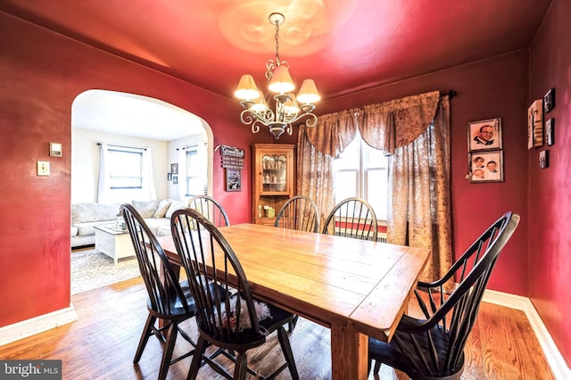 dining space featuring hardwood / wood-style flooring, an inviting chandelier, and a wealth of natural light