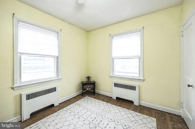 spare room with radiator heating unit and dark wood-type flooring