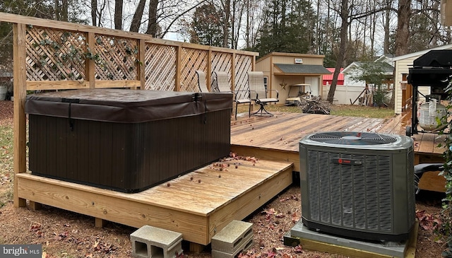 wooden deck with central AC unit, a hot tub, and a storage shed