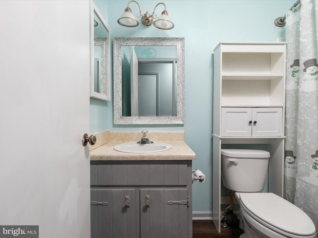 bathroom with toilet, baseboards, and vanity