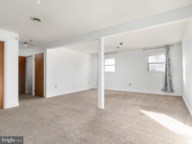 below grade area featuring baseboards, visible vents, and light colored carpet