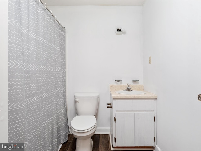 full bath with toilet, wood finished floors, vanity, and baseboards