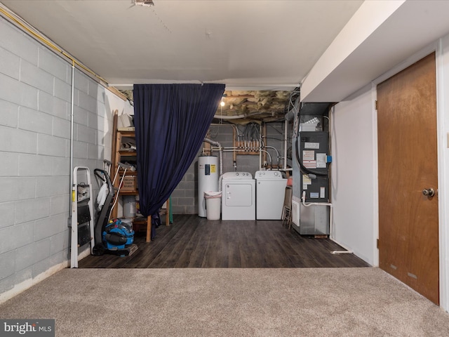 finished basement featuring concrete block wall, dark wood-style flooring, washing machine and clothes dryer, heating unit, and water heater