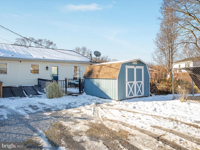 snow covered structure featuring an outbuilding and a storage unit