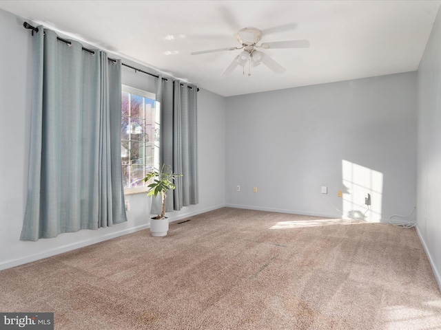 spare room featuring carpet floors, ceiling fan, visible vents, and baseboards