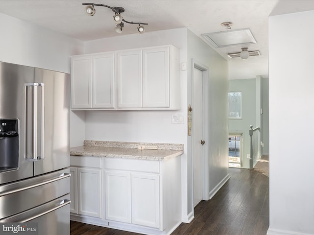 kitchen with dark wood-style flooring, visible vents, white cabinetry, high quality fridge, and baseboards