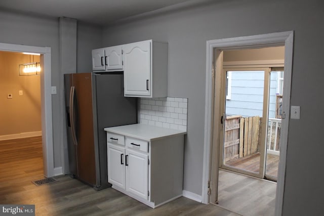 kitchen with stainless steel fridge with ice dispenser, decorative backsplash, white cabinetry, and hardwood / wood-style floors