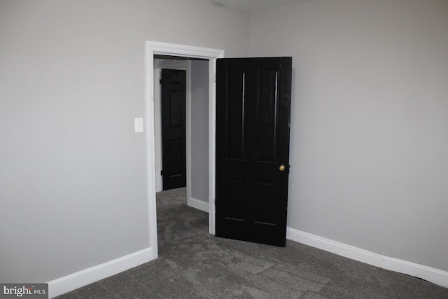 unfurnished room with dark carpet