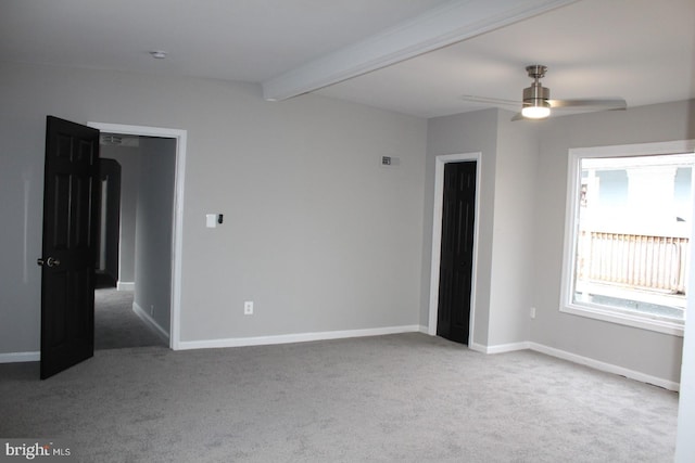 carpeted empty room with ceiling fan and beam ceiling