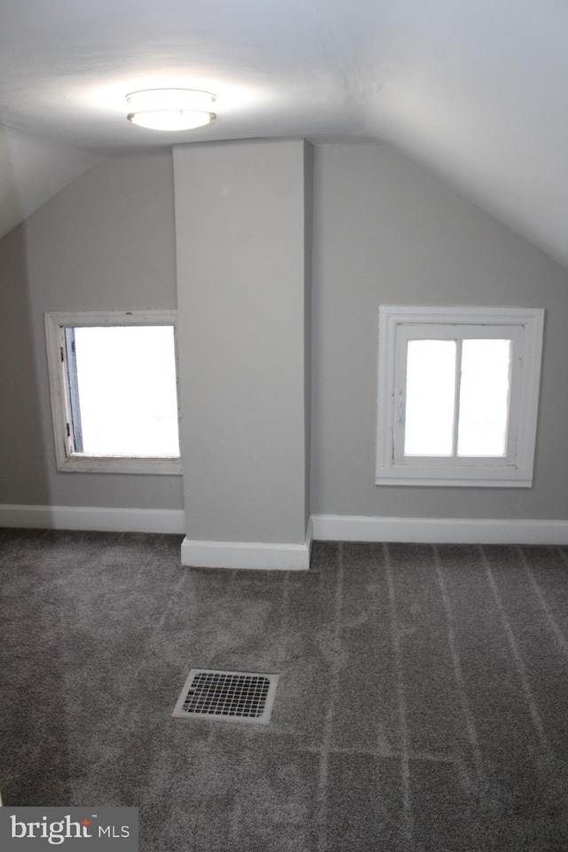 bonus room featuring lofted ceiling and dark colored carpet