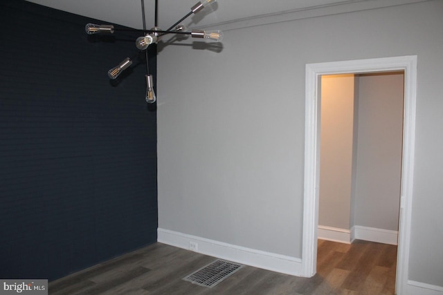 unfurnished room featuring a chandelier and dark wood-type flooring