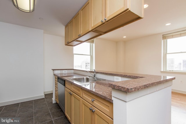 kitchen featuring dishwasher, sink, light brown cabinets, dark tile patterned floors, and an island with sink