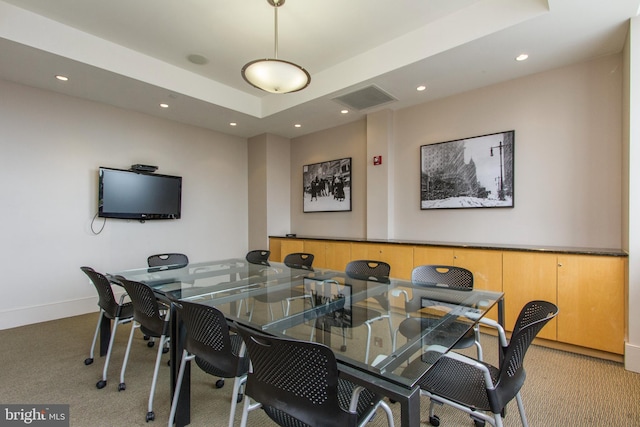 dining area with light colored carpet and a raised ceiling