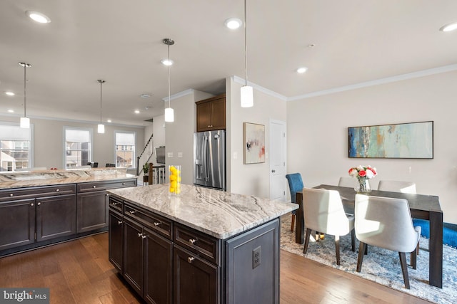 kitchen with stainless steel refrigerator with ice dispenser, dark hardwood / wood-style floors, a kitchen island, and hanging light fixtures