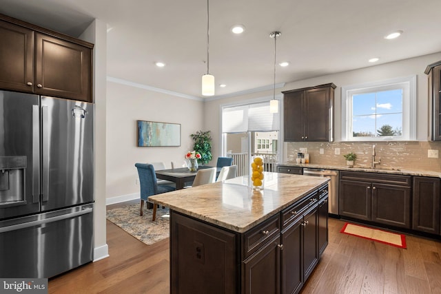 kitchen with sink, hanging light fixtures, dark wood-type flooring, a kitchen island, and appliances with stainless steel finishes