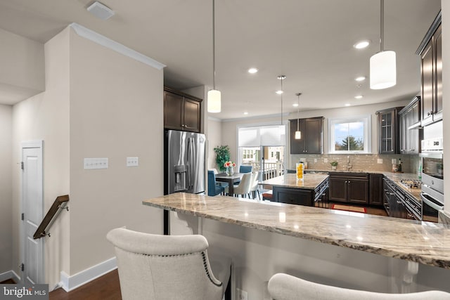 kitchen featuring dark hardwood / wood-style flooring, light stone counters, hanging light fixtures, and stainless steel appliances