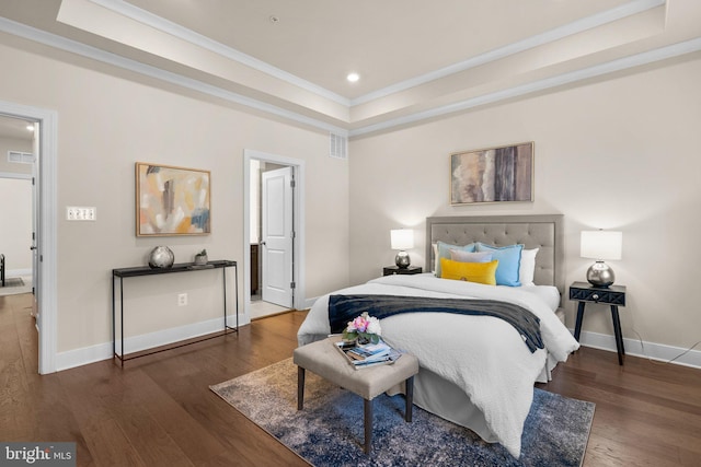 bedroom with dark hardwood / wood-style floors, ensuite bath, crown molding, and a tray ceiling