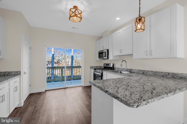 kitchen featuring white cabinets, sink, hanging light fixtures, dark hardwood / wood-style flooring, and stainless steel appliances