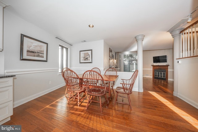 dining area with ornate columns and hardwood / wood-style floors