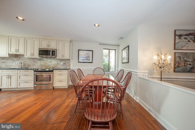 dining area with hardwood / wood-style floors, sink, and a chandelier