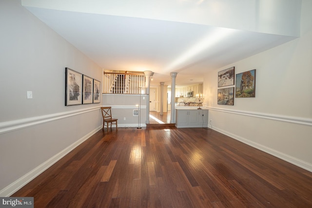 unfurnished living room with dark hardwood / wood-style floors and ornate columns