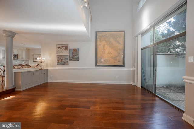 interior space featuring decorative columns and dark wood-type flooring